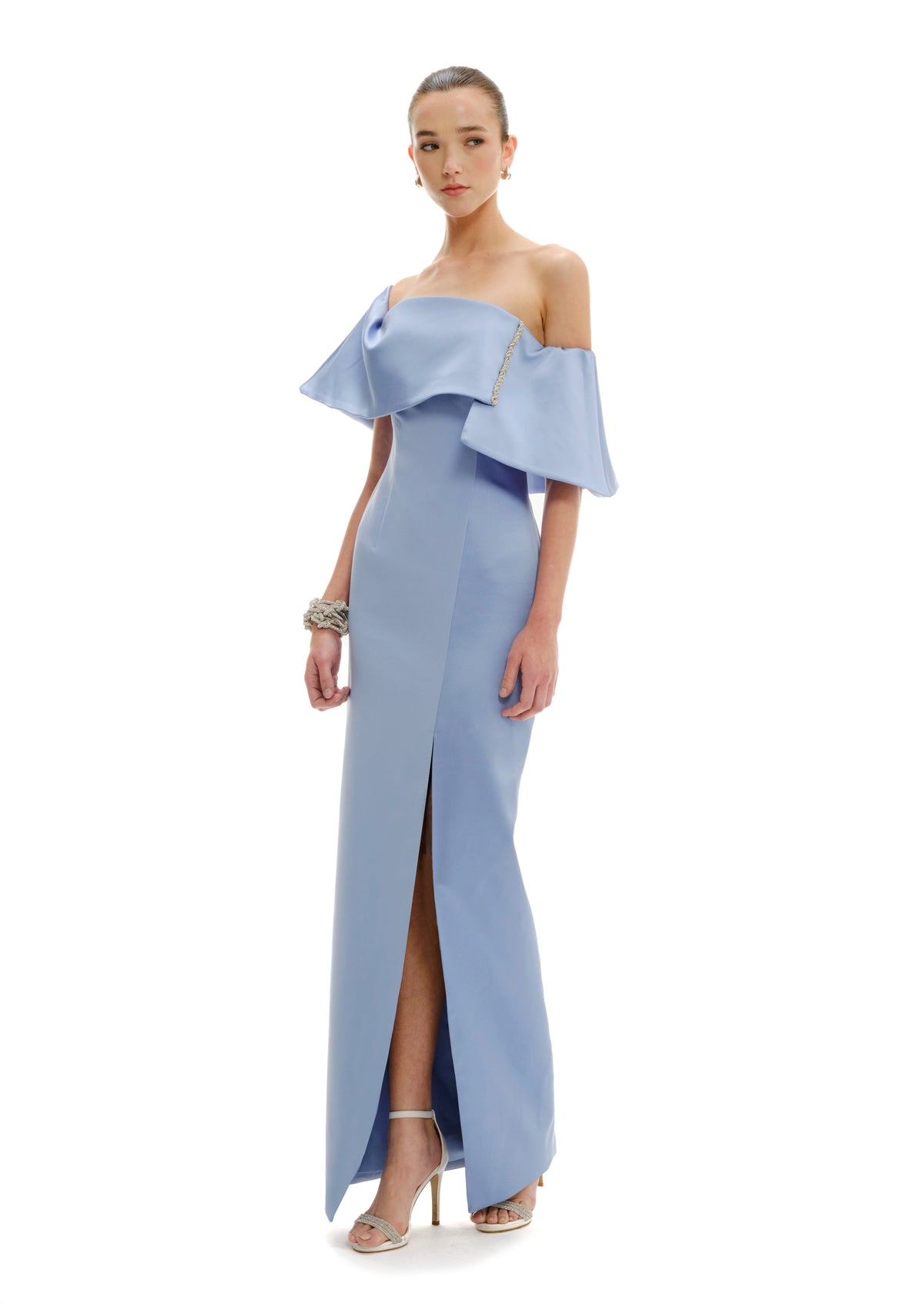 Model wearing Avaro Figlio celestial blue off-shoulder gown with ruffled details on a white background
