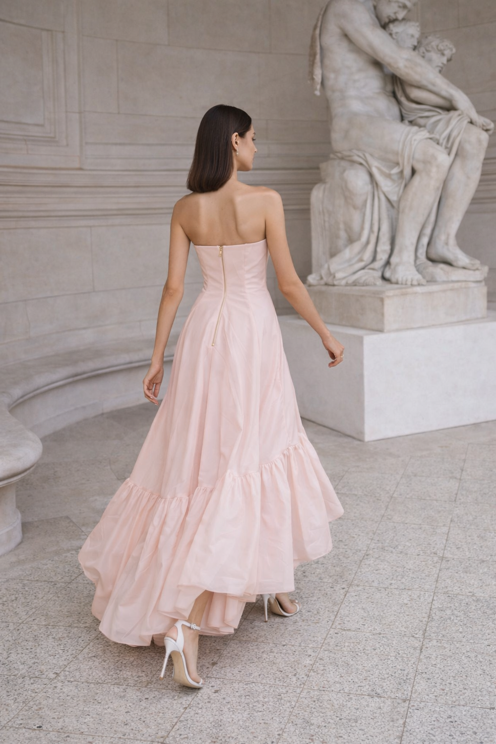 Model walking through marble Milanese hallway in draped SS26 gown, editorial light study