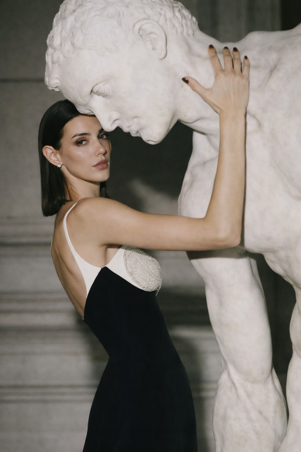 Woman in a black dress touching a marble sculpture