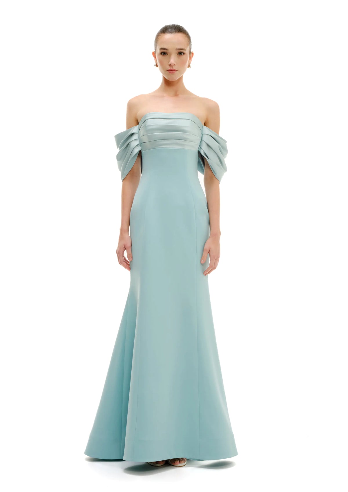 A woman modeling a floor-length Avaro Figlio off-the-shoulder maxi dress in pastel green, photographed against a plain white studio background.