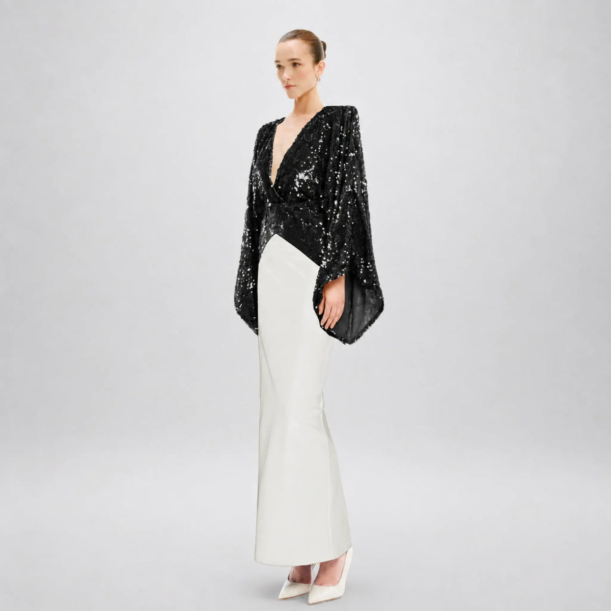 Model wearing a black sequin kimono dress with a white cady skirt in an elegant setting.