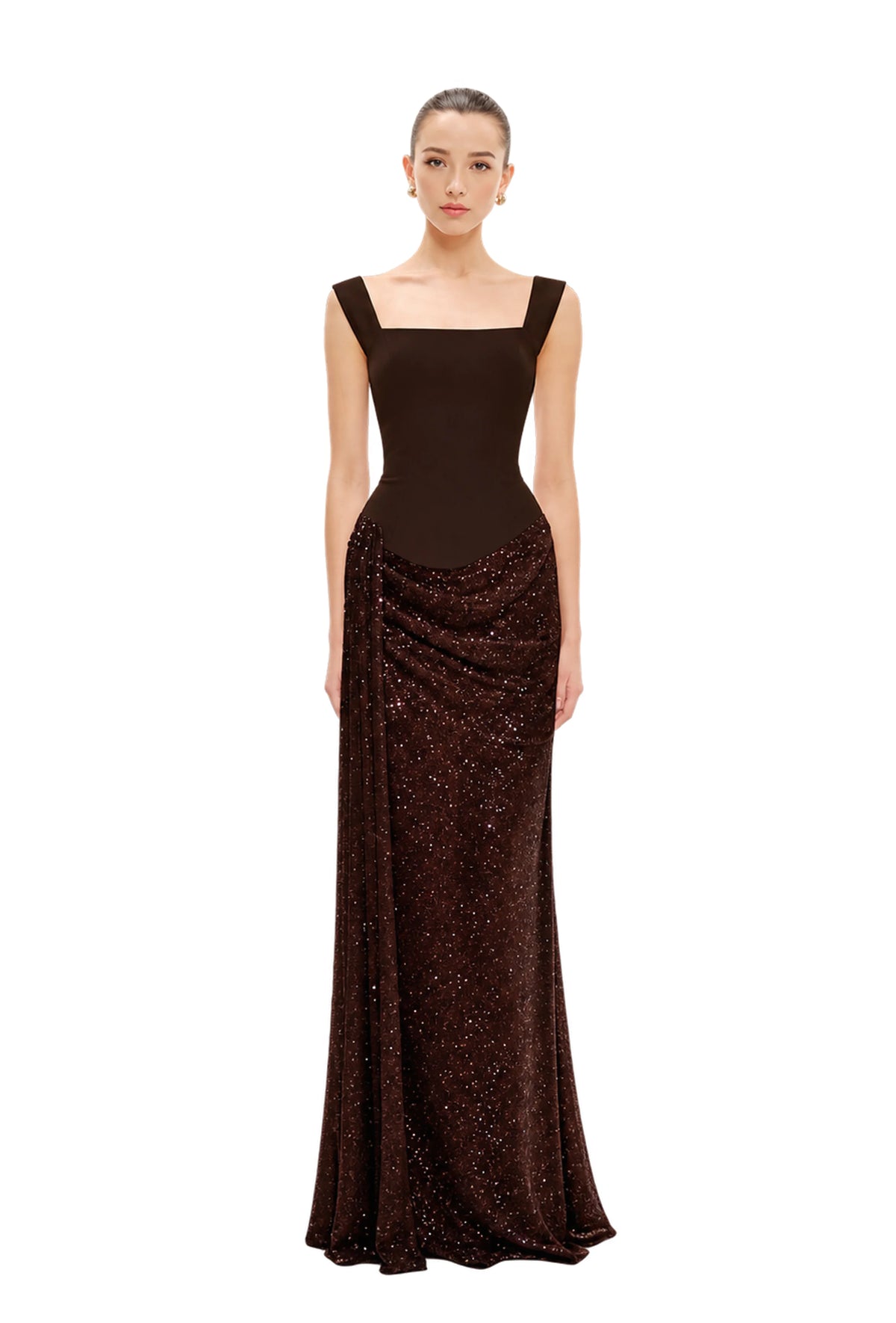 A model wearing a floor-length, dark brown Avaro Figlio evening gown with a square neckline and shimmering sequined detailing on the skirt, set against a plain light gray studio background.