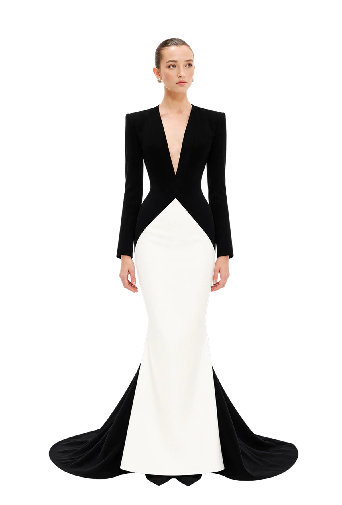 A model wearing a long-sleeved black and white Avaro Figlio mermaid gown with a deep V-neckline and structured shoulders, set against a plain light gray studio background.