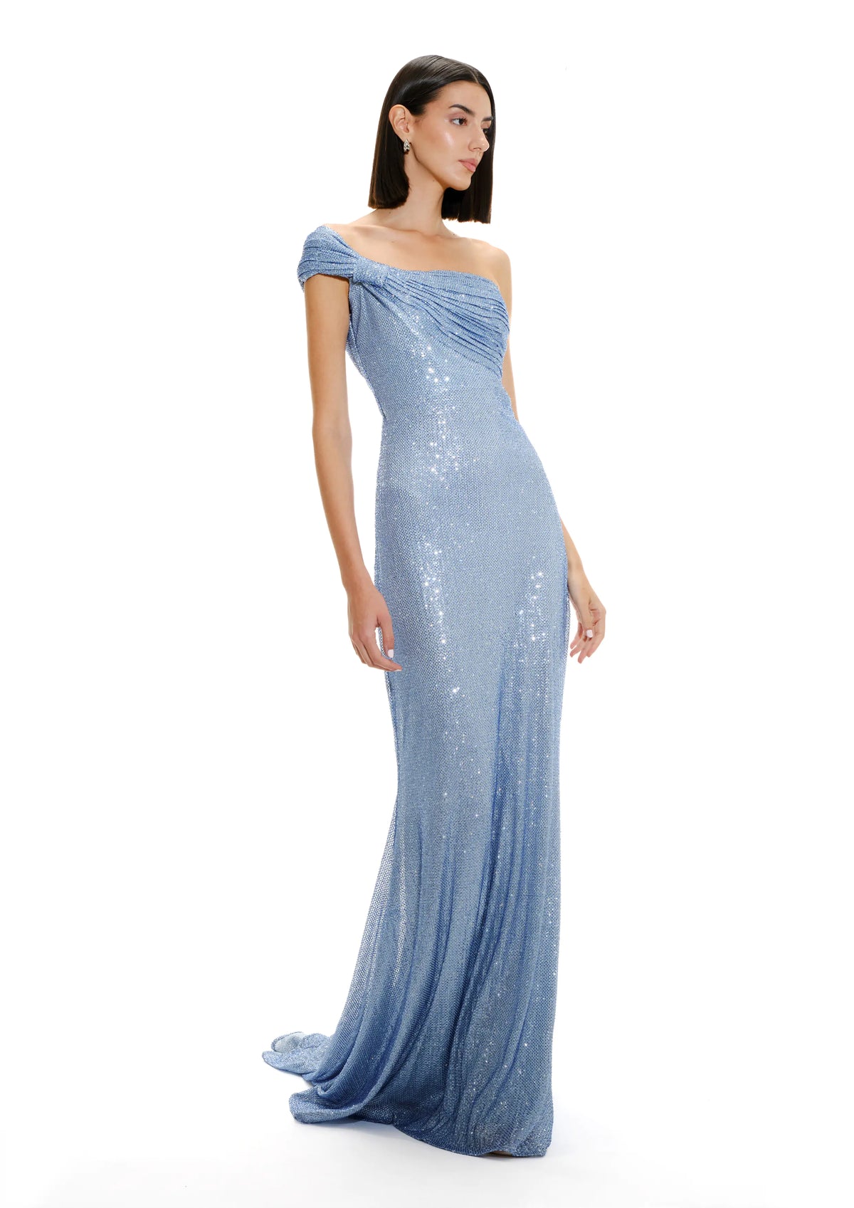 Model wearing Avaro Figlio floor-length, one-shoulder evening dress covered in shimmering light blue sequins against a plain white studio background.