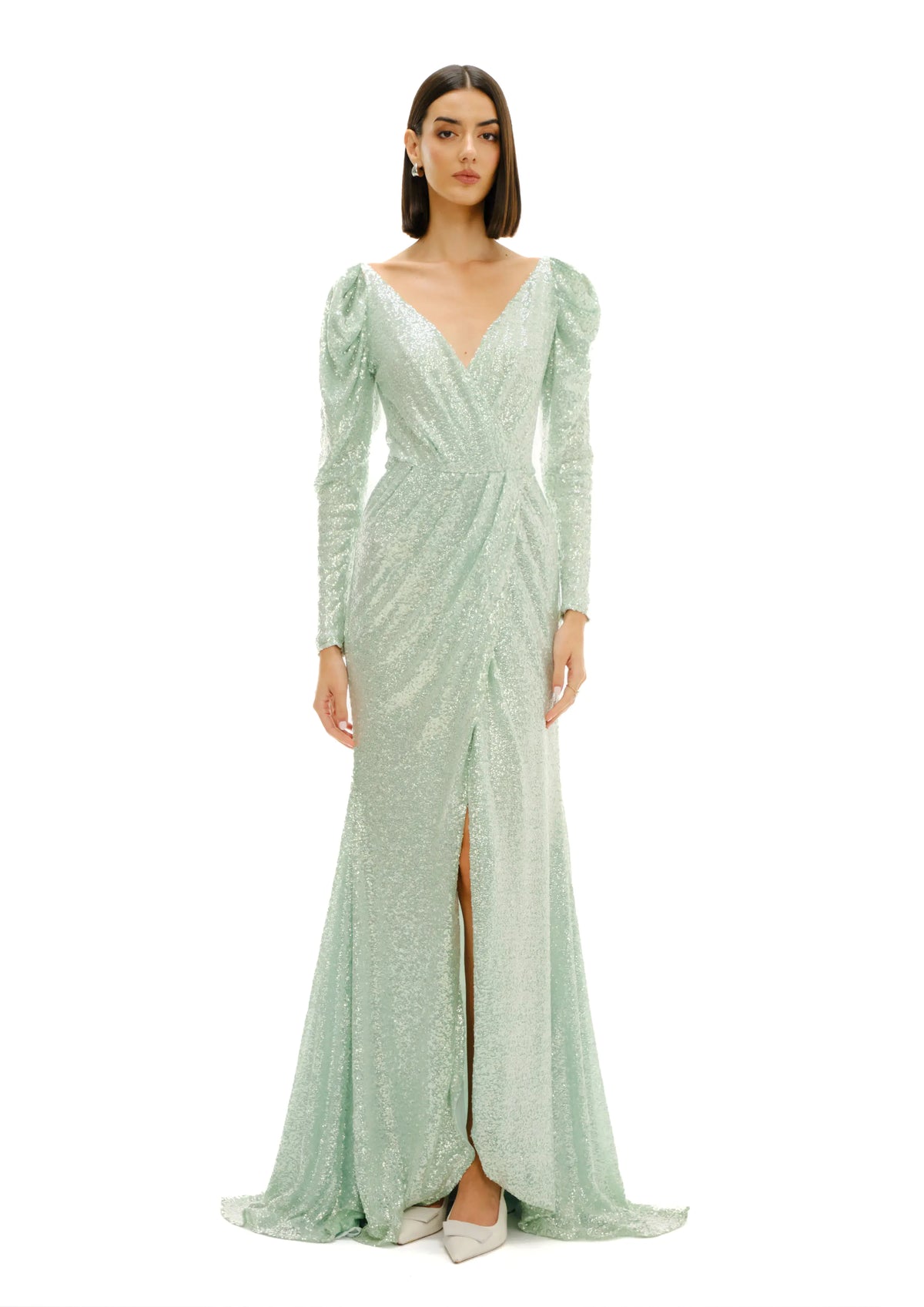 A model wearing a floor-length Avaro Figlio green sequined gown with long puff sleeves, a deep V-neckline, and a thigh-high front slit, photographed against a solid white background.