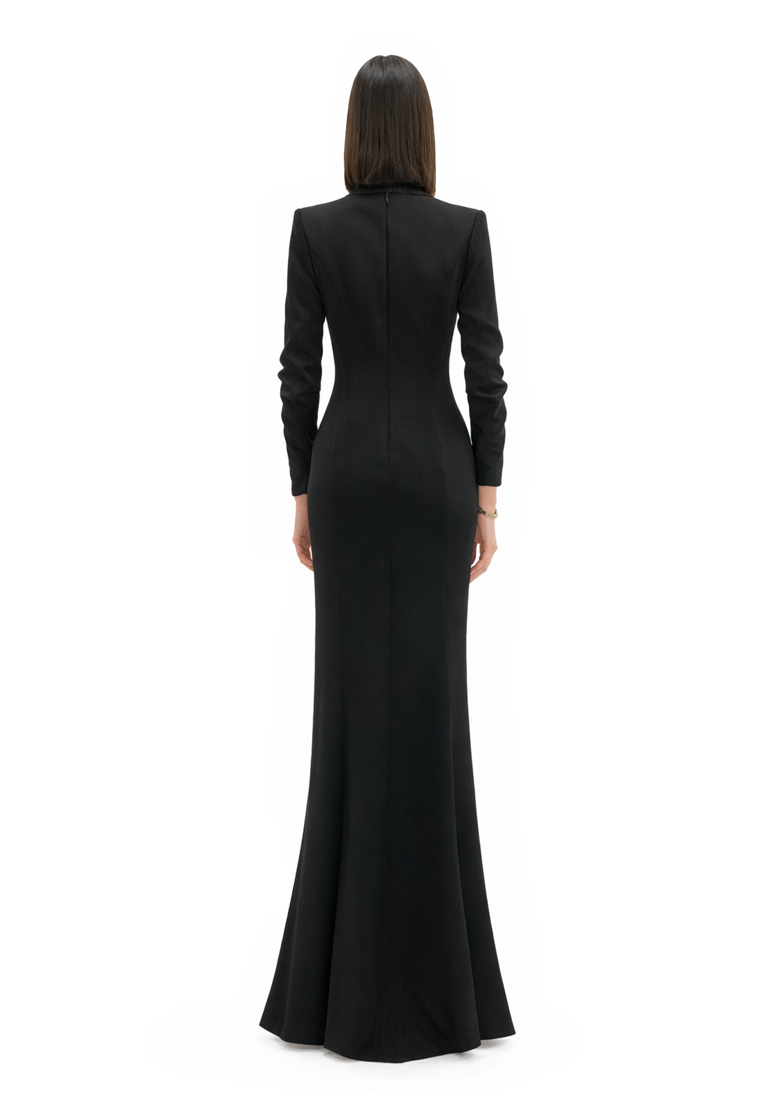 Back view of model wearing black blazer gown with slit showcasing structured shoulders, zip closure, and tailored floor-length column silhouette by Avaro Figlio