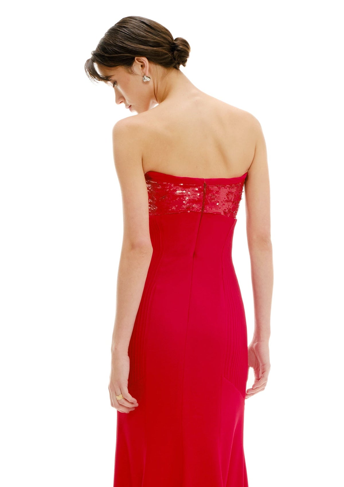 Woman wearing a red strapless gown with sequin detailing on a white background